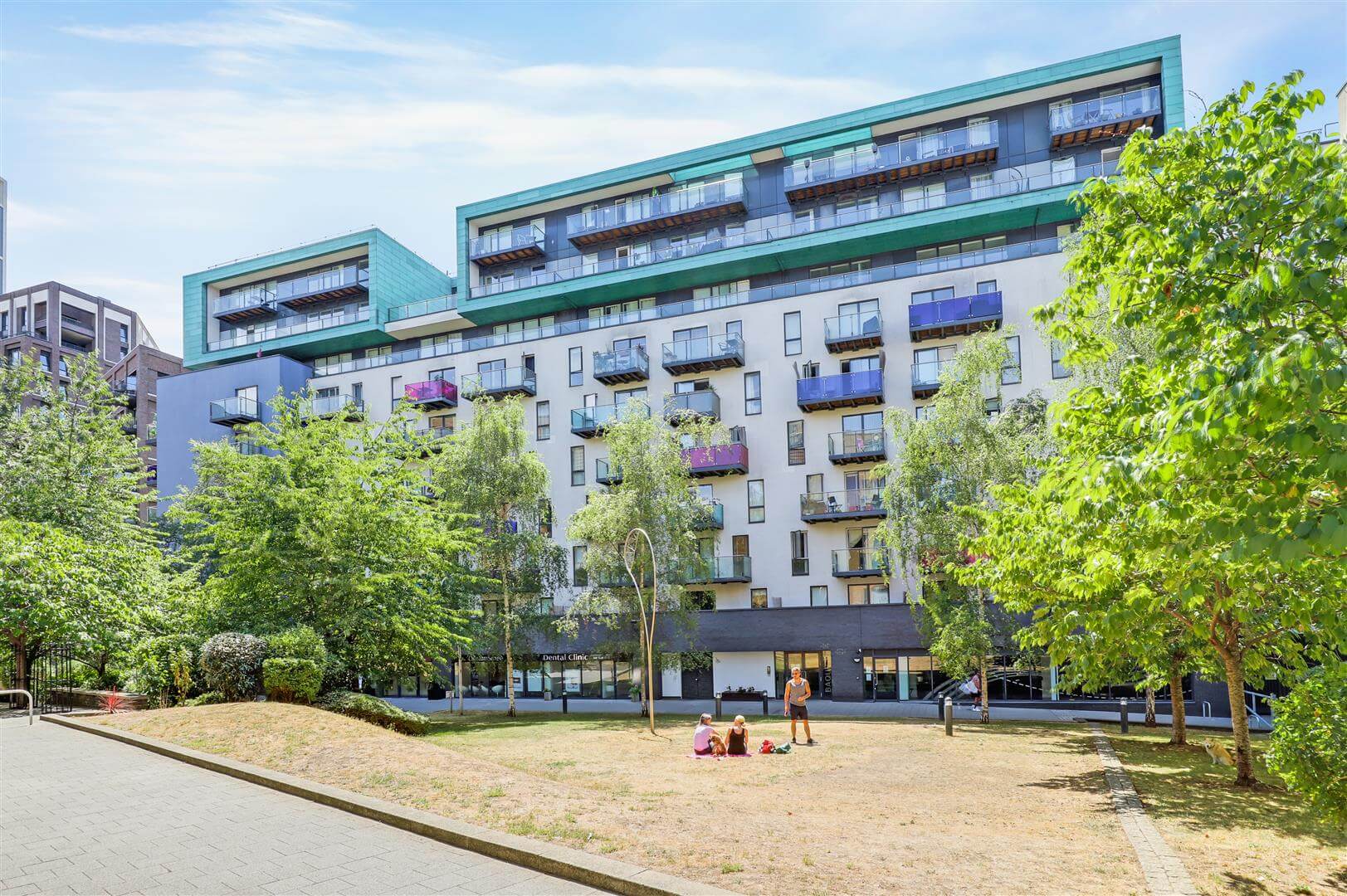 External view of a block of apartments with a grassed lawn area to the front and a number of trees and shrubs