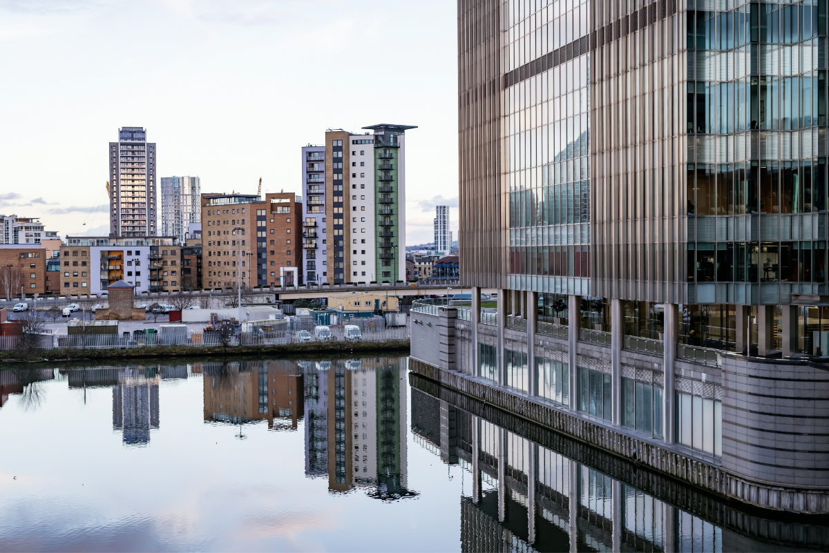City view of residential and commercial buildings reflecting into a body of water