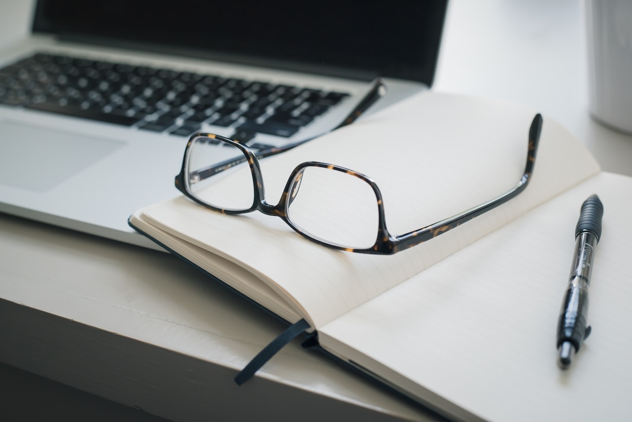 Reading glasses sat in front of laptop on a not pad