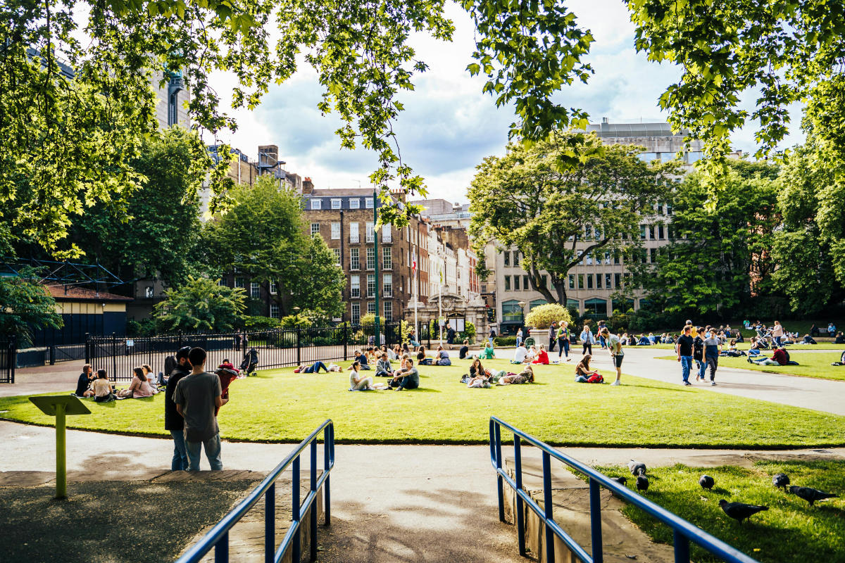 A sunny day in london with a park full of people all doing different activities