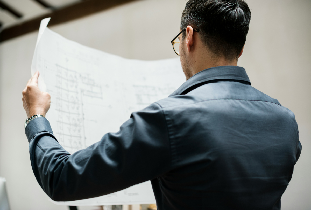 A person studies a large building plan on a sheet of paper