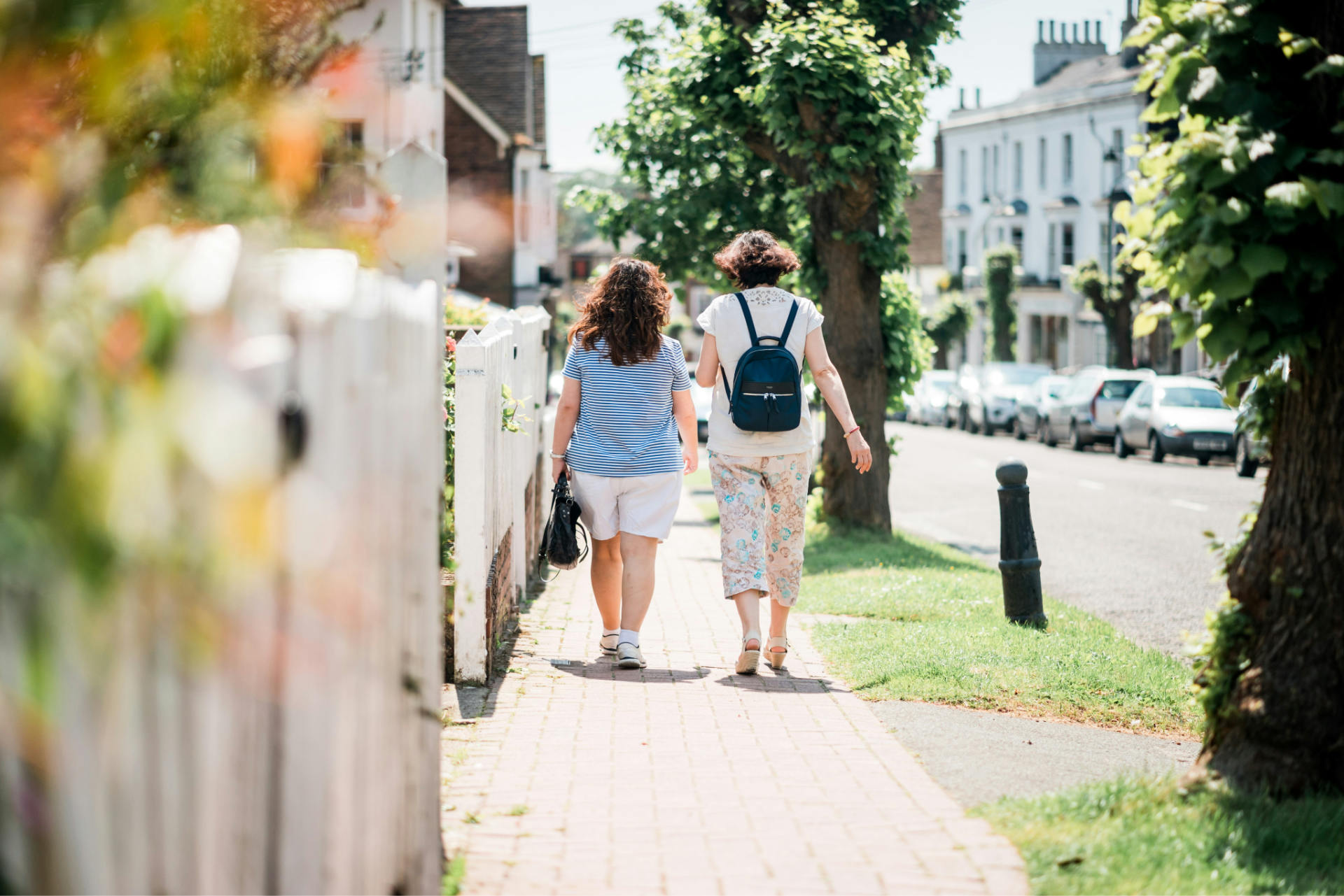 2 people walking down a street with lots of trees