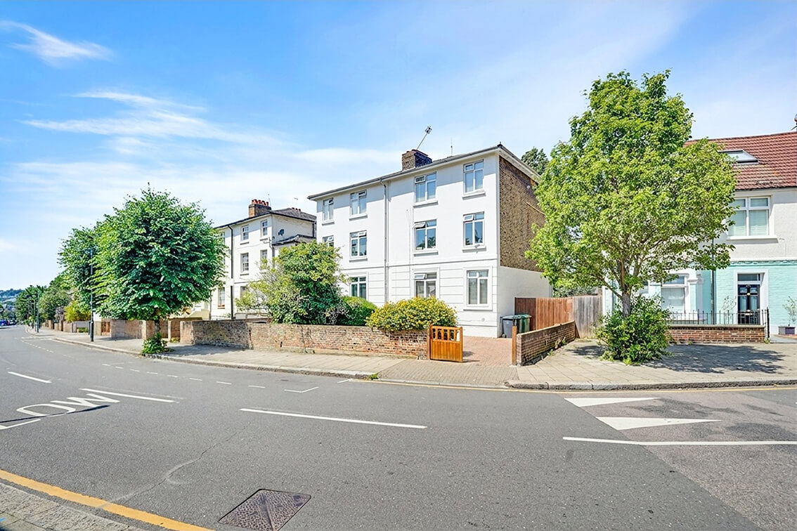 External view of a three storey terraced property on the corner of Allfarthing Road, with perimeter wall and gated driveway.
