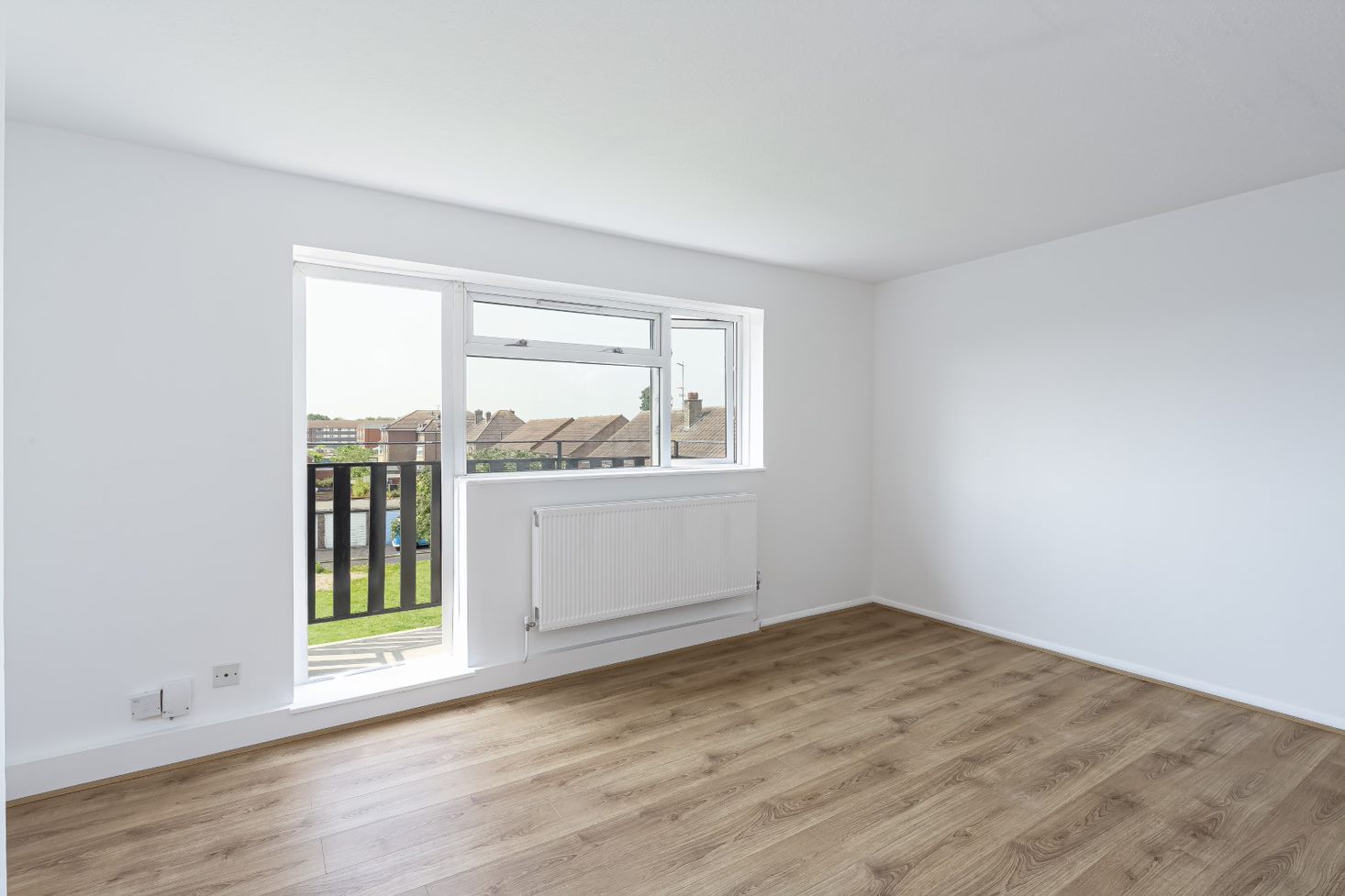 Refurbished reception room, with white walls, radiator, wooden flooring, double glazed windows and door which provides balcony access