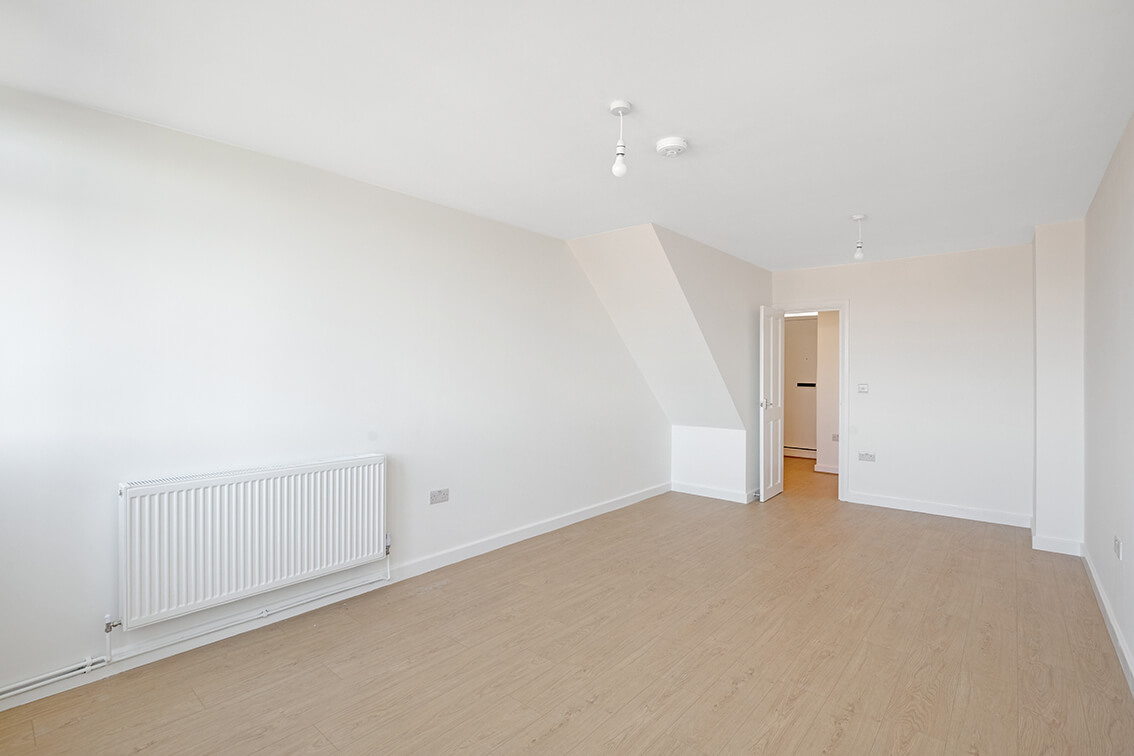 Newly refurbished living space with white walls, radiator and wooden flooring