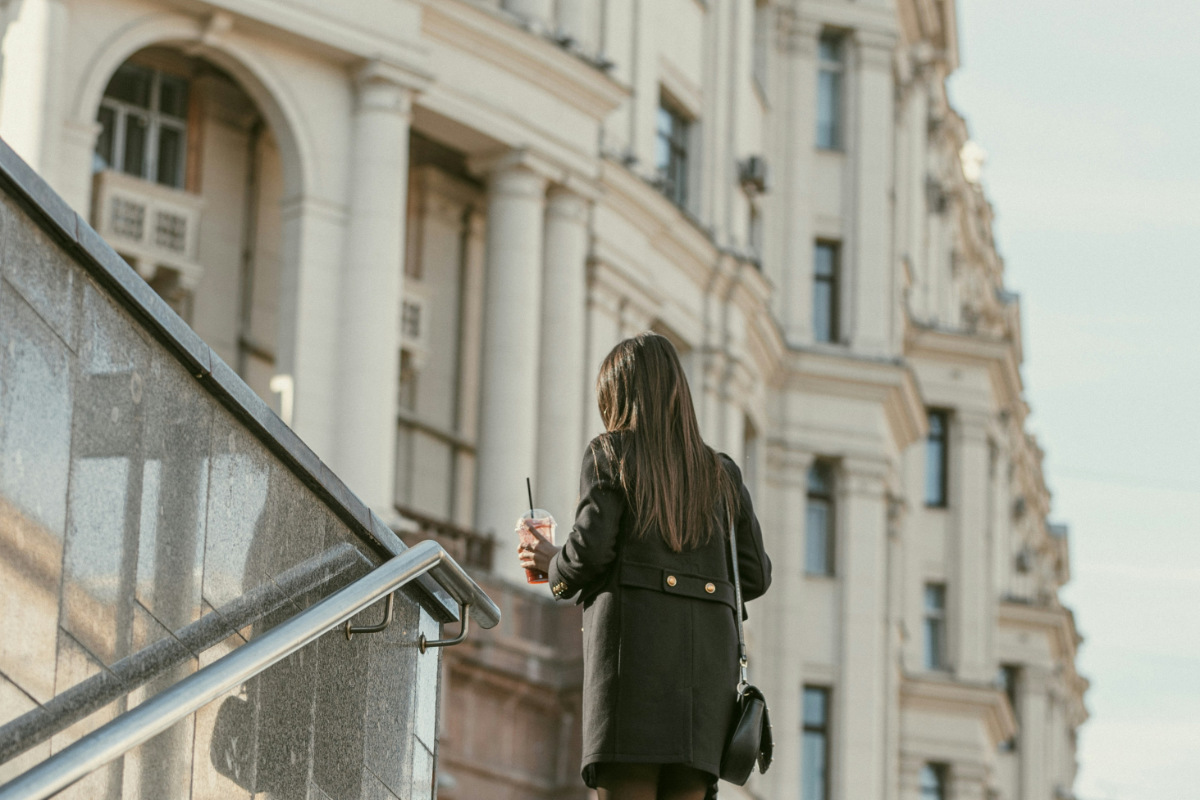 A commuter leaves the train station with a coffee