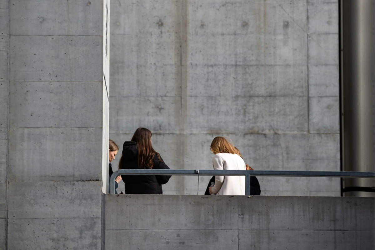 A group of workers meet outside a concrete building to discuss a refurbishment project