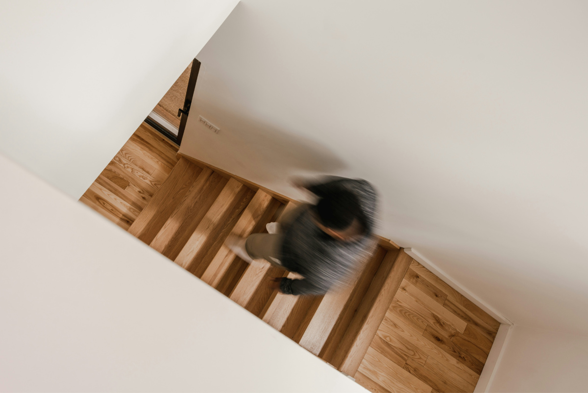 A person walks down some wooden stairs in a house