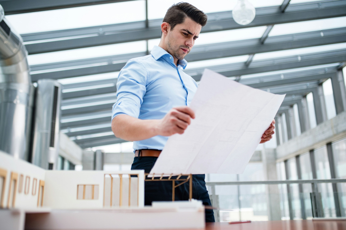 A person studies a architect's building model and a printed plan